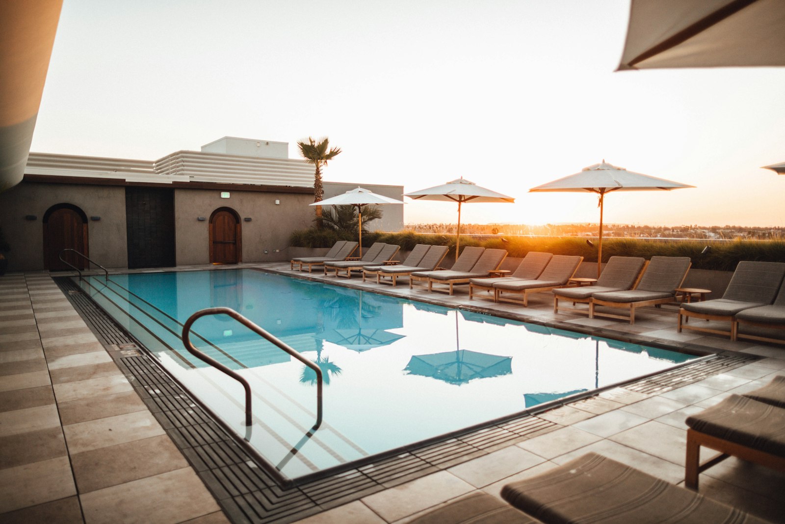 A sleek rectangular pool with loungers and umbrellas at golden hour