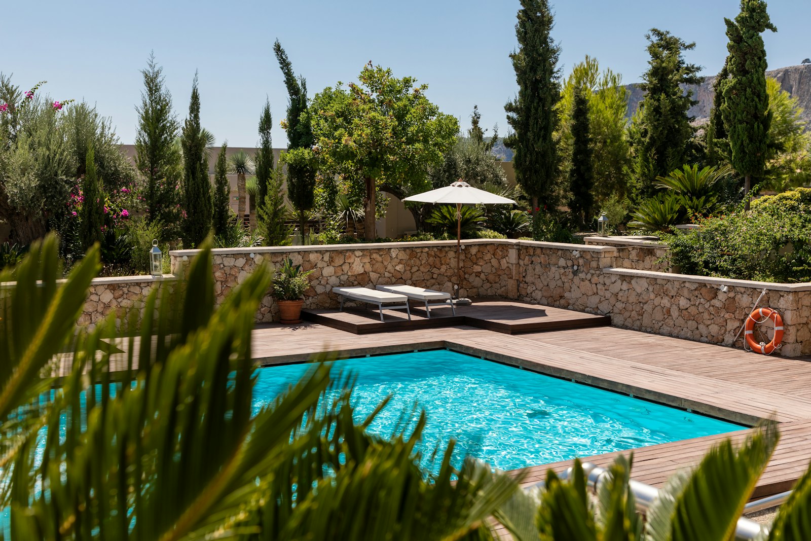 A backyard swimming pool with a stone wall and desert landscaping in Southern Utah